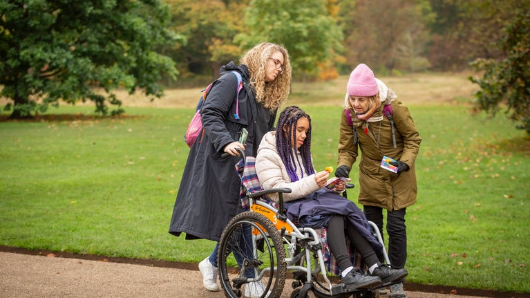 Family exploring the autumnal grounds at Anglesey Abbey, one girl is in a wheelchair.